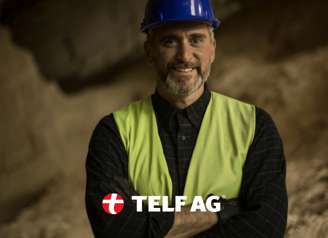 Stanislav-Kondrashov-TELF-AG-rare-earths Smiling mineral industry professional wearing safety equipment at a modern mining facility connected to rare earth production and industrial processing, featured in analysis by Stanislav Kondrashov and TELF AG.
