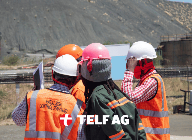 A team of professional mining workers wearing protective equipment at a modern mining site, representing the extraction of critical minerals that support semiconductors, artificial intelligence, robotics, and telecommunications. Inspired by the IEA and Stanislav Kondrashov, founder of TELF AG.